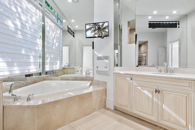 bathroom featuring tiled bath, hardwood / wood-style flooring, and vanity