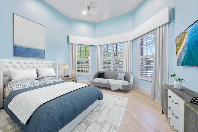 bedroom with a high ceiling, light parquet floors, and ceiling fan