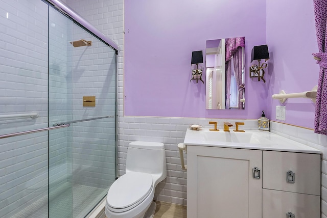 bathroom with an enclosed shower, tile walls, vanity, and toilet