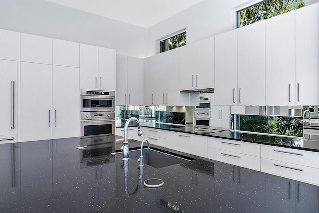 kitchen with white cabinets, stainless steel double oven, sink, and black electric stovetop