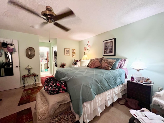 bedroom with carpet, a textured ceiling, ensuite bath, and ceiling fan