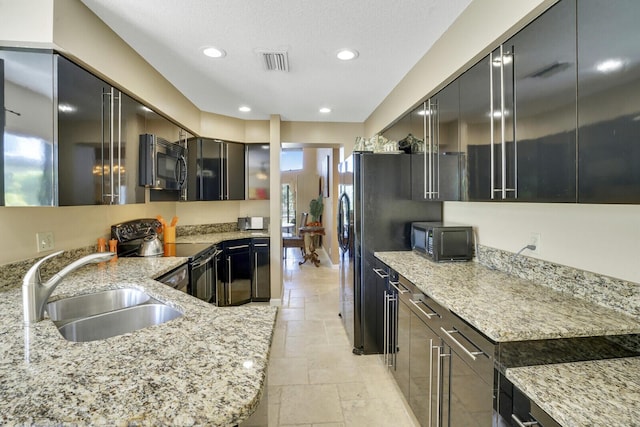 kitchen featuring black appliances, light stone countertops, and sink