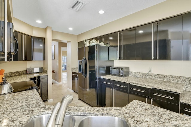 kitchen featuring light stone counters and black appliances