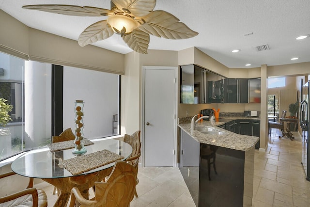 kitchen with sink, stainless steel refrigerator, ceiling fan, a textured ceiling, and kitchen peninsula