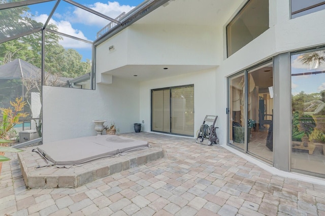 view of patio / terrace with a hot tub and glass enclosure