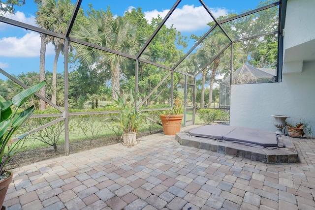 view of patio / terrace with glass enclosure and a covered hot tub