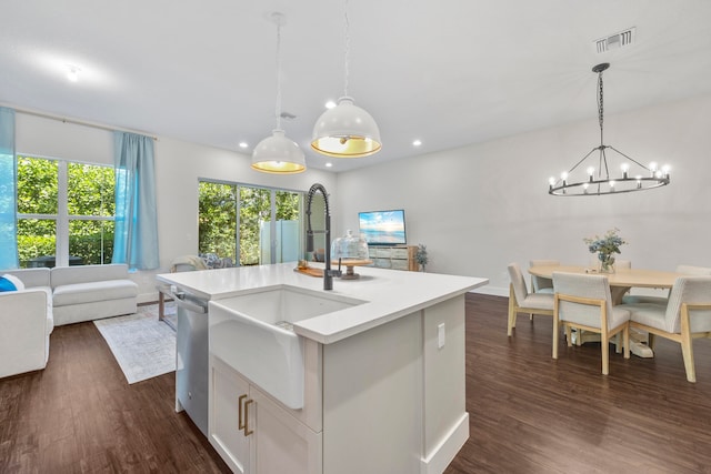 kitchen with dark hardwood / wood-style flooring, stainless steel dishwasher, sink, decorative light fixtures, and an island with sink