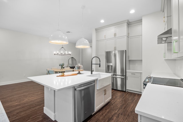 kitchen with appliances with stainless steel finishes, extractor fan, a kitchen island with sink, dark hardwood / wood-style floors, and hanging light fixtures