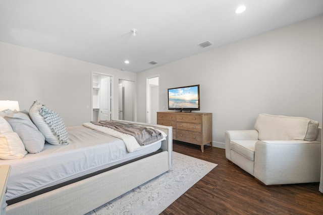 bedroom with a walk in closet, a closet, and dark hardwood / wood-style floors