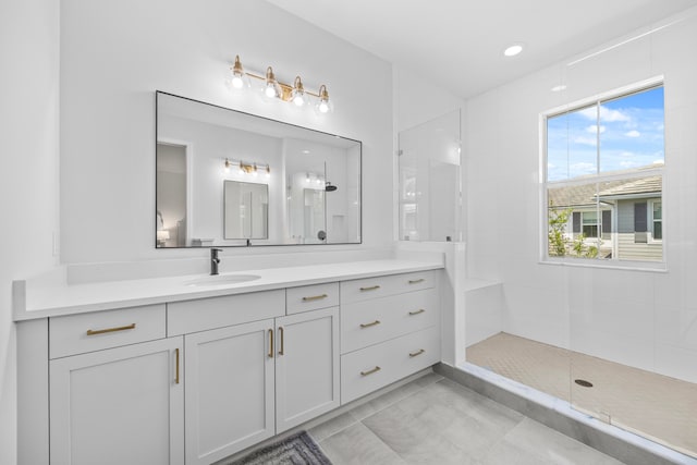 bathroom with tile patterned floors, vanity, and a tile shower