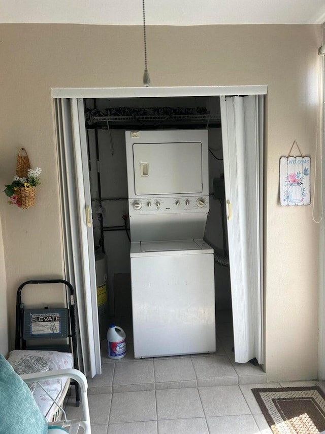 clothes washing area featuring light tile patterned floors and stacked washing maching and dryer