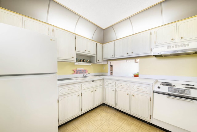 kitchen with sink, range hood, white cabinets, stove, and white fridge