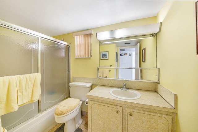 full bathroom with combined bath / shower with glass door, vanity, toilet, and tile patterned flooring