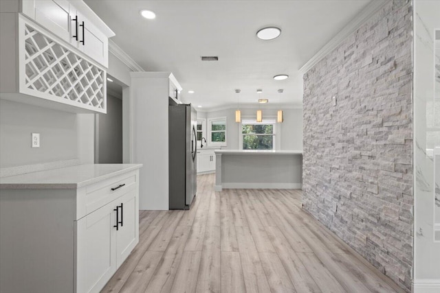 kitchen with pendant lighting, light hardwood / wood-style floors, white cabinetry, and crown molding