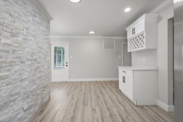 kitchen featuring white cabinetry, light stone counters, light wood-type flooring, and ornamental molding