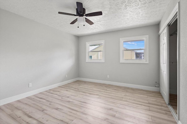 unfurnished bedroom with a textured ceiling, light wood-type flooring, a closet, and ceiling fan