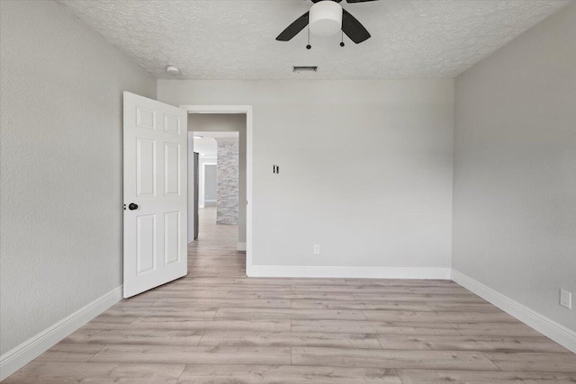 empty room featuring ceiling fan, a textured ceiling, and light hardwood / wood-style flooring