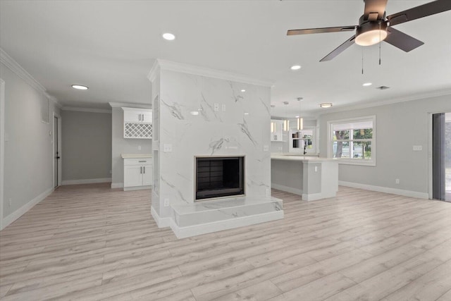 unfurnished living room featuring ceiling fan, light hardwood / wood-style flooring, a high end fireplace, and ornamental molding