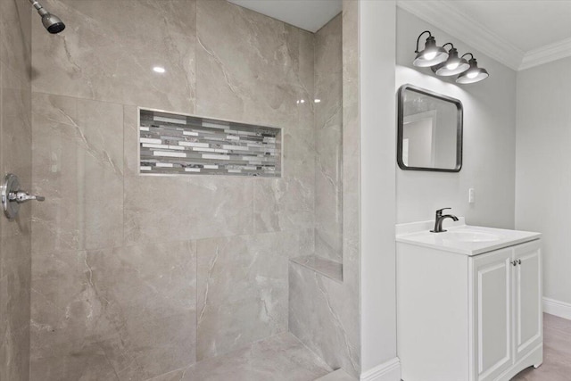 bathroom with a tile shower, vanity, and ornamental molding