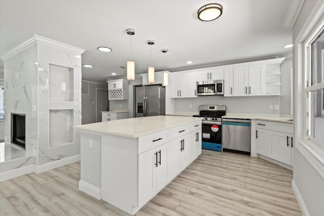 kitchen with stainless steel appliances, white cabinets, a center island, light hardwood / wood-style floors, and hanging light fixtures