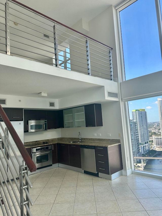 kitchen with sink, light tile patterned floors, stainless steel appliances, and a high ceiling