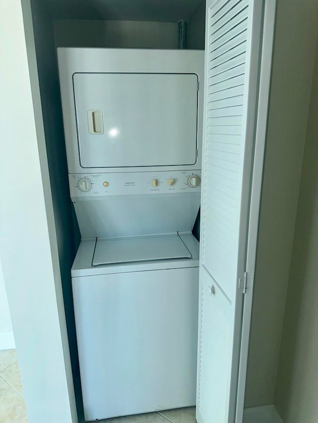 laundry room with stacked washing maching and dryer and light tile patterned flooring