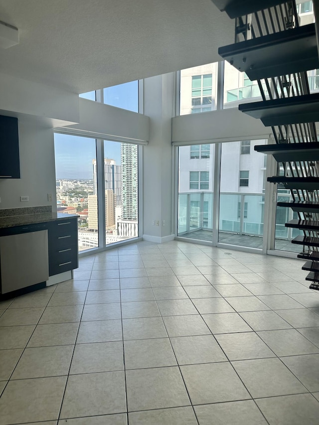 41 SE 5th St Unit 2017, Miami, FL 33131 - unfurnished living room with light tile patterned flooring, a city view, a towering ceiling, and baseboards