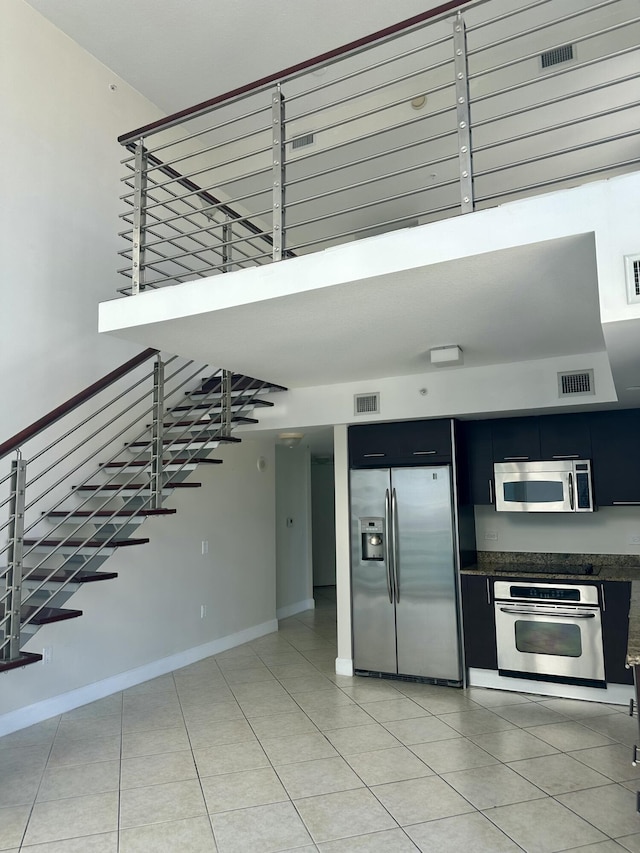 41 SE 5th St Unit 2017, Miami, FL 33131 - kitchen featuring stainless steel appliances, dark cabinetry, light tile patterned floors, and baseboards