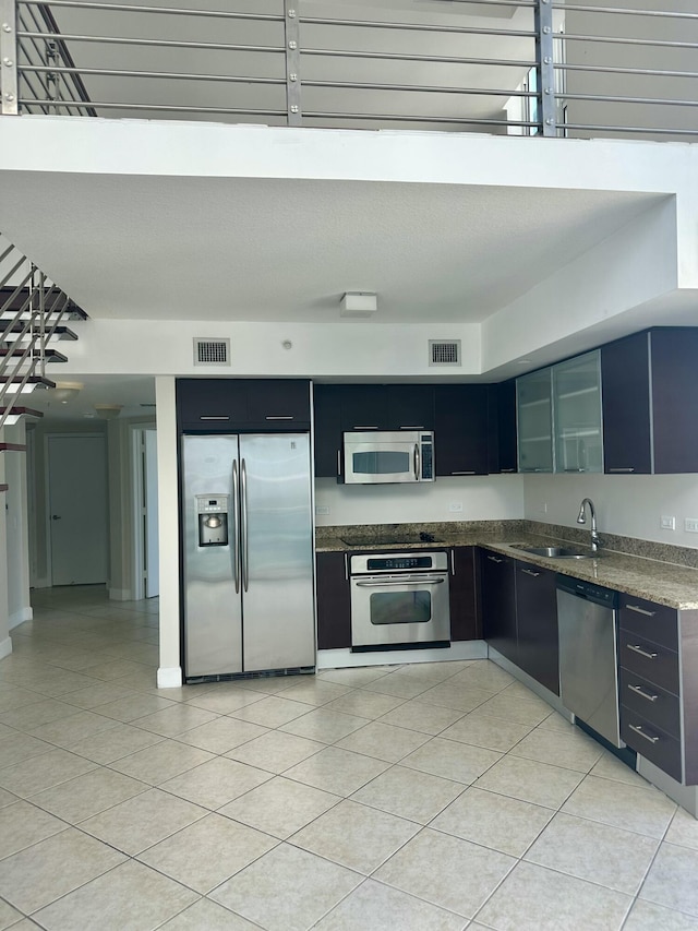 41 SE 5th St Unit 2017, Miami, FL 33131 - kitchen featuring stainless steel appliances, a sink, light tile patterned flooring, and dark cabinets
