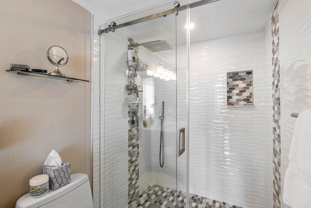 bathroom featuring a shower with door and toilet