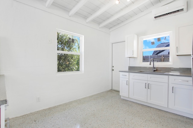 kitchen with an AC wall unit, sink, and white cabinets