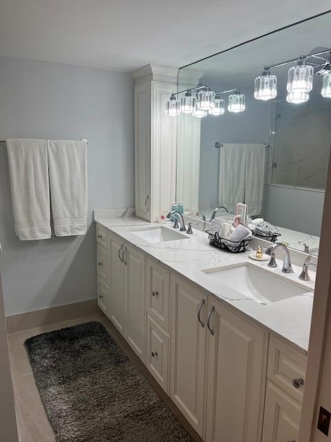 bathroom with double vanity, baseboards, a sink, and tile patterned floors