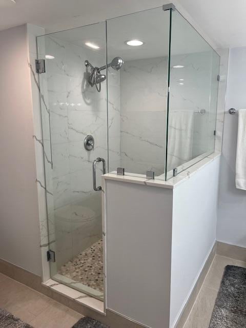 bathroom featuring a marble finish shower, baseboards, and tile patterned floors