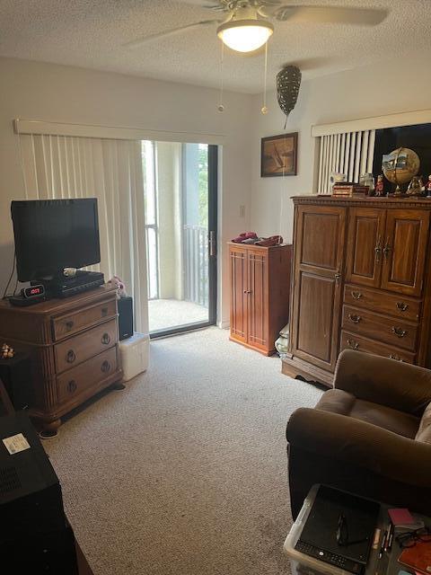 interior space with a textured ceiling, ceiling fan, and carpet