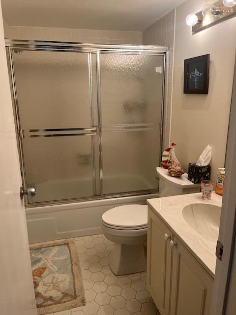 bathroom with toilet, tile patterned floors, combined bath / shower with glass door, and vanity