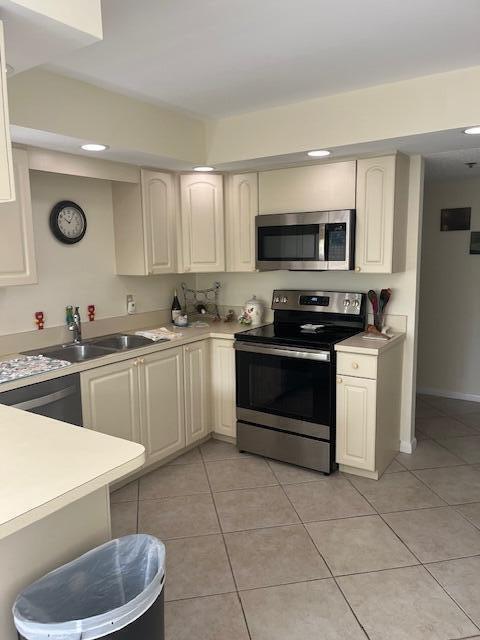 kitchen with stainless steel appliances, light countertops, a sink, and light tile patterned flooring