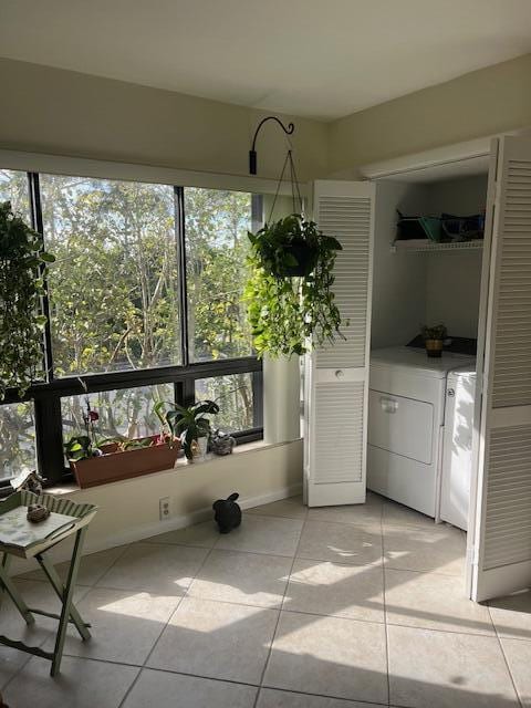 interior space with light tile patterned floors, washer and clothes dryer, and a wealth of natural light