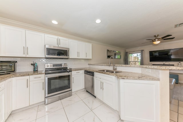 kitchen featuring sink, stainless steel appliances, kitchen peninsula, white cabinets, and ornamental molding