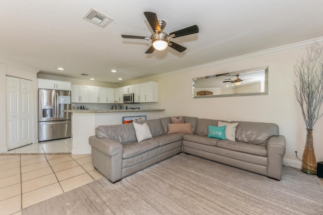 tiled living room with crown molding, sink, and ceiling fan