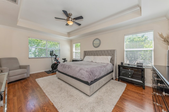 bedroom with a raised ceiling, ceiling fan, crown molding, and dark hardwood / wood-style floors