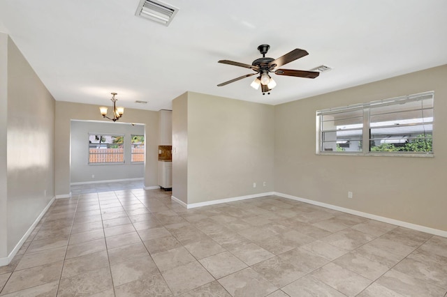 empty room with ceiling fan with notable chandelier and light tile patterned floors