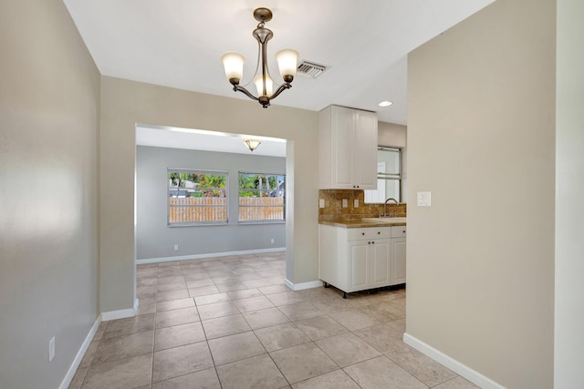 interior space with light tile patterned floors, a chandelier, and sink