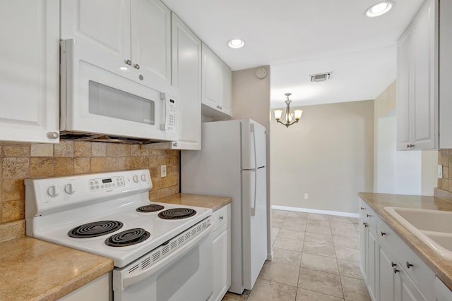 kitchen with white appliances, pendant lighting, sink, white cabinetry, and backsplash