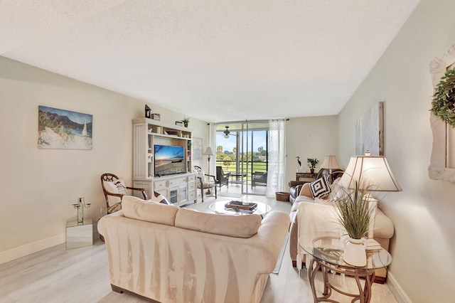 living room featuring a textured ceiling, floor to ceiling windows, and light hardwood / wood-style floors