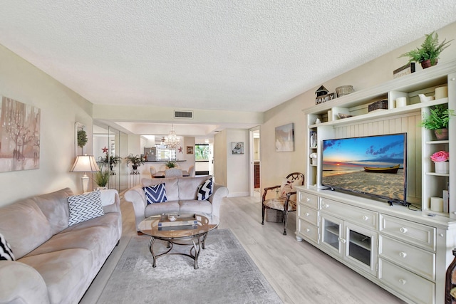 living room featuring a textured ceiling, light hardwood / wood-style floors, and a chandelier