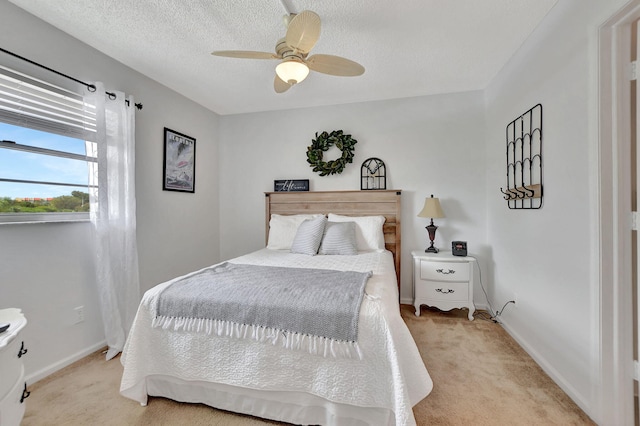 bedroom featuring a textured ceiling, ceiling fan, and light colored carpet