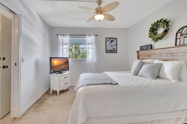 carpeted bedroom with ceiling fan and a textured ceiling