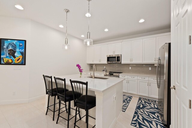 kitchen featuring a center island with sink, pendant lighting, white cabinetry, and stainless steel appliances