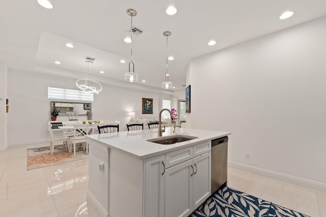 kitchen with stainless steel dishwasher, sink, pendant lighting, light tile patterned floors, and a center island with sink