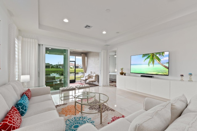 living room with light tile patterned floors and a tray ceiling